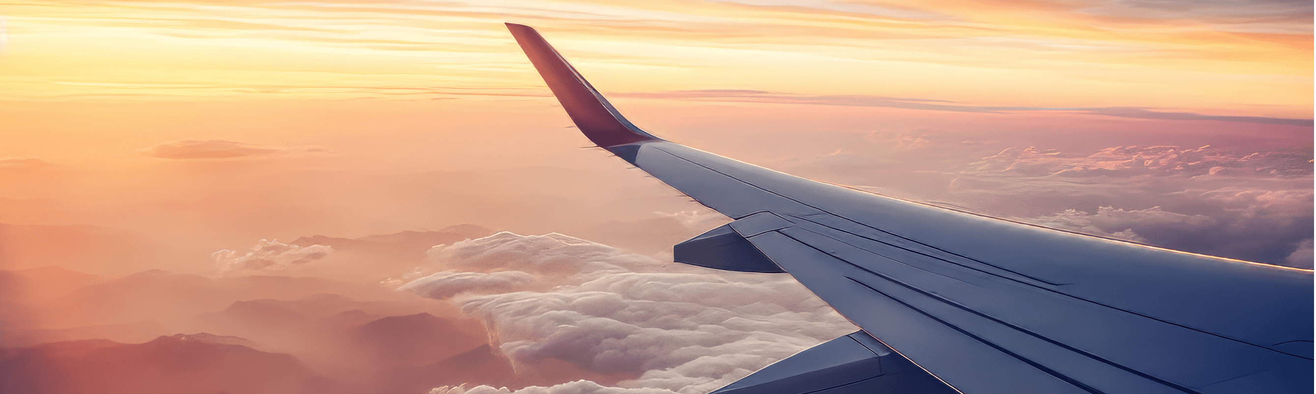 Airplane wing above clouds at sunset